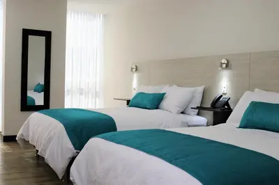 a hotel room with two beds and a mirror at Arame Hotel in Envigado