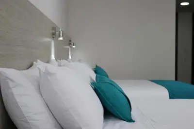 a bed with white and blue pillows on it at Arame Hotel in Envigado