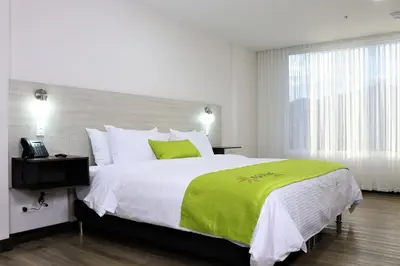 a bedroom with a large bed with a green blanket at Arame Hotel in Envigado