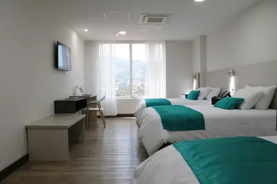 a hotel room with two beds and a desk at Arame Hotel in Envigado