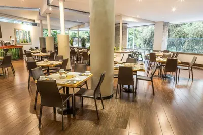 a restaurant with wooden tables and chairs and large windows at Four Points by Sheraton Medellín in Medellín