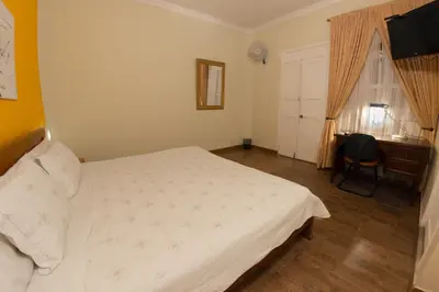 a bedroom with a white bed and a desk at 61Prado Hotel in Medellín