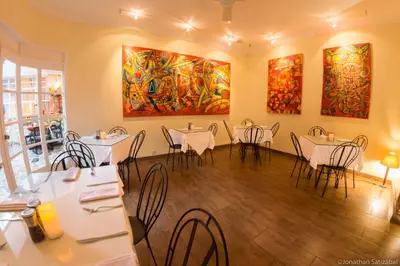a dining room with tables and chairs and paintings at 61Prado Hotel in Medellín