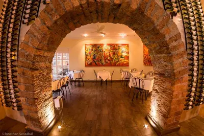 a room with tables and chairs and a painting at 61Prado Hotel in Medellín