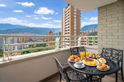 a table with breakfast foods on a balcony with a view at Apartamentos Poblado Alejandría by HOUSY in Medellín