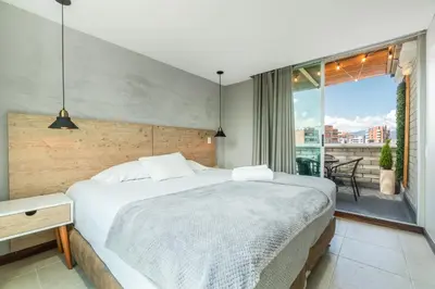 a bedroom with a large bed and a balcony at Apartamentos Poblado Alejandría by HOUSY in Medellín