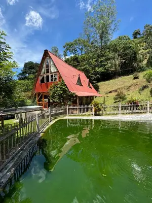 a house with a red roof next to a pond at Hotel Campestre la Playa in Betania