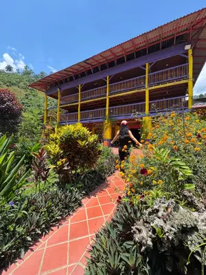 a woman standing in front of a building with flowers at Hotel Campestre la Playa in Betania