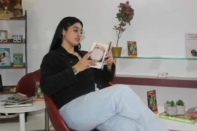 a woman sitting in a chair reading a book at Hotel Florencia Plaza in Medellín