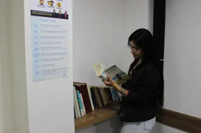 a woman reading a book next to a shelf at Hotel Florencia Plaza in Medellín