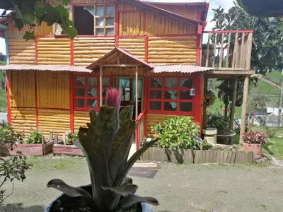 a wooden house with red windows in front of it at Finca Hotel Nutabes in San Pedro
