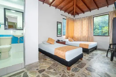 a bedroom with two beds and a bathroom at Hotel Barcelona Estadio in Medellín