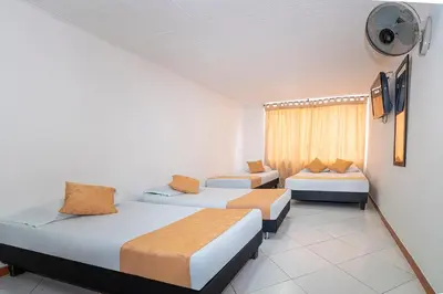 a room with three beds and a window at Hotel Barcelona Estadio in Medellín