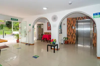 a lobby with a red table and a revolving door at Hotel Barcelona Estadio in Medellín