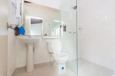 a bathroom with a toilet and a glass shower at Hotel Suite del Parque in Medellín
