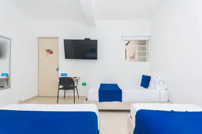 a bedroom with a bed and a tv on the wall at Hotel Suite del Parque in Medellín