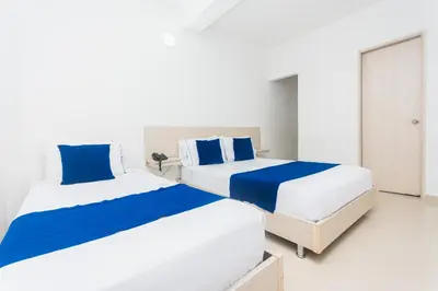 two beds in a bedroom with blue and white at Hotel Suite del Parque in Medellín