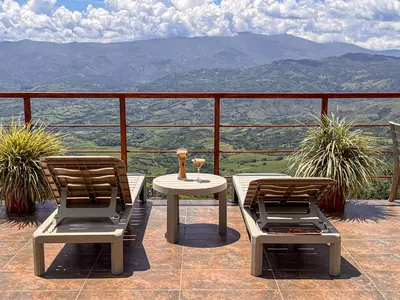 a table and chairs on a balcony with a view of mountains at Finca Hotel Los Guayacanes in San JosÃ©