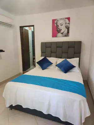 a bedroom with a large bed with blue pillows at Hosteria El Castellano in Santa Fe de Antioquia