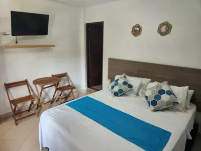 a bedroom with a bed with a television and chairs at Hosteria El Castellano in Santa Fe de Antioquia