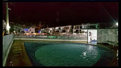a pool of green water at night with buildings at Apartasol Santafe de Antioquia in Santa Fe de Antioquia
