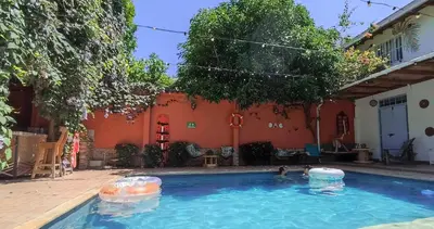 two people are swimming in a swimming pool at Hotel Casa de Verano - Solo adultos - in Santa Fe de Antioquia