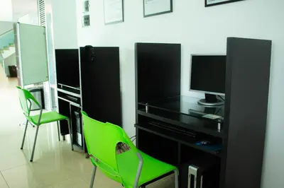 a computer desk with a monitor and a green chair at Hotel Central Plaza Medellin in Medellín