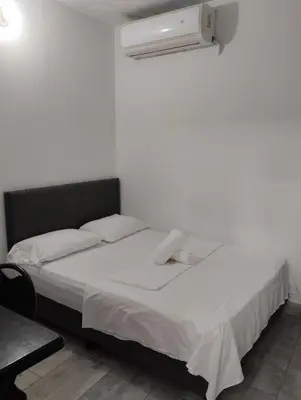 a bedroom with a white bed with a fan at Hotel Ozzy in Doradal