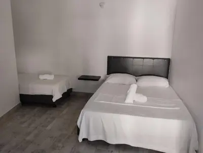 a bedroom with two beds with white sheets at Hotel Ozzy in Doradal