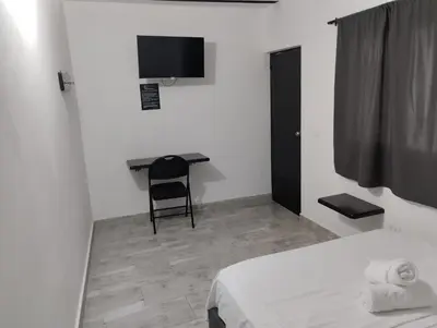a bedroom with a desk and a bed and a chair at Hotel Ozzy in Doradal