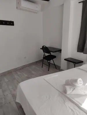 a bedroom with a white bed and a black chair at Hotel Ozzy in Doradal