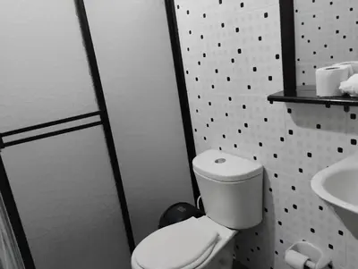 a bathroom with a toilet and a sink at Hotel Ozzy in Doradal