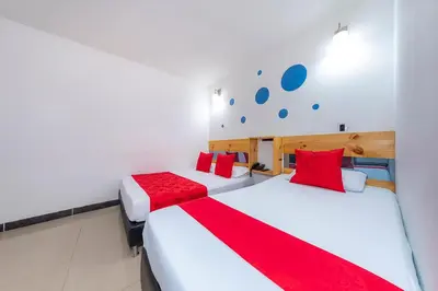 two beds in a room with red and white sheets at Hotel Confort Obelisk in Medellín