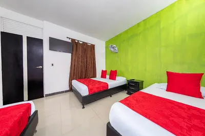 two beds in a room with red and green walls at Hotel Confort Obelisk in Medellín