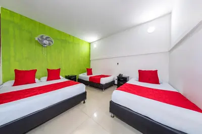 two beds in a room with red and green walls at Hotel Confort Obelisk in Medellín
