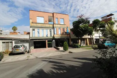 a building with a car parked in front of a street at Hotel Confort Obelisk in Medellín