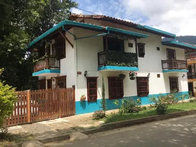 a white and blue house with a wooden fence at Casa Huespedes EL ENSUEÑO in Jardin