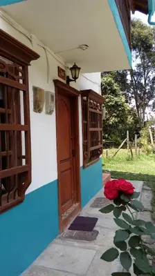 a house with a door and red flowers on the ground at Casa Huespedes EL ENSUEÑO in Jardin