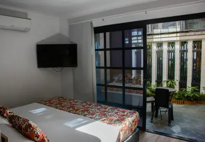 a bedroom with a bed and a tv and a window at Hotel Poma Rosa in Medellín