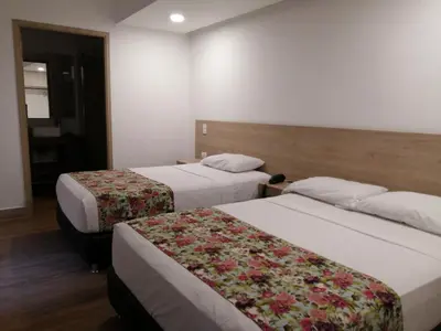 a hotel room with two beds with flowers on them at Hotel Poma Rosa in Medellín