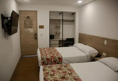 a hotel room with two beds and a sliding door at Hotel Poma Rosa in Medellín