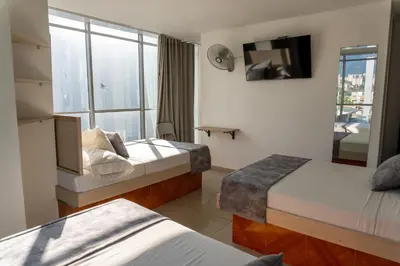 a hotel room with two beds and a window at Hotel Alcaravan Medellín in Medellín