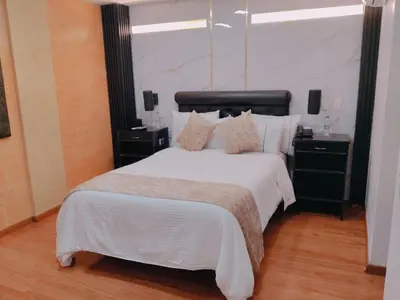 a bedroom with a large bed with white sheets and pillows at Hotel Veler in Medellín