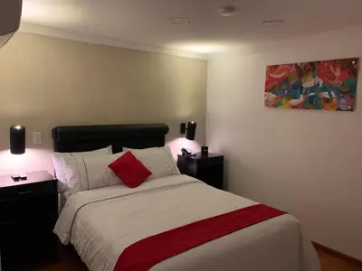 a bedroom with a bed with two lamps and a painting at Hotel Veler in Medellín