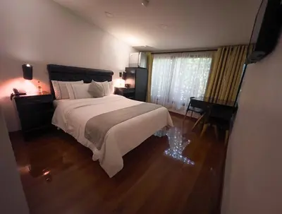 a bedroom with a bed and a desk and a window at Hotel Veler in Medellín