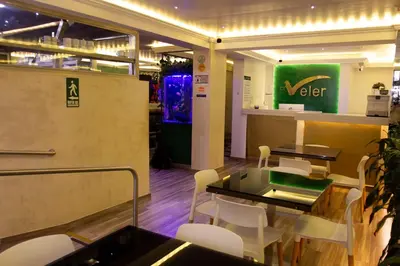 a restaurant with white chairs and a table and a counter at Hotel Veler in Medellín