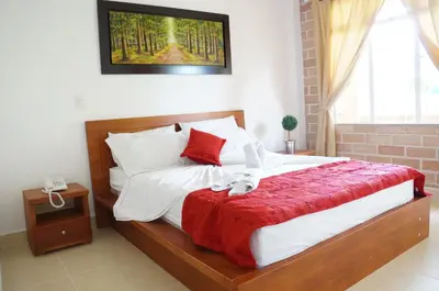 a bedroom with a large bed with a red blanket at Hostería Fundadores in Santa Fe de Antioquia