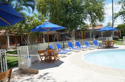 a group of chairs and umbrellas next to a pool at Hostería Fundadores in Santa Fe de Antioquia