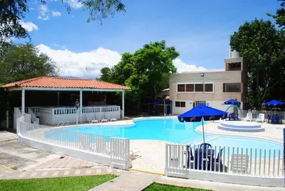a pool with chairs and umbrellas and a building at Hostería Fundadores in Santa Fe de Antioquia