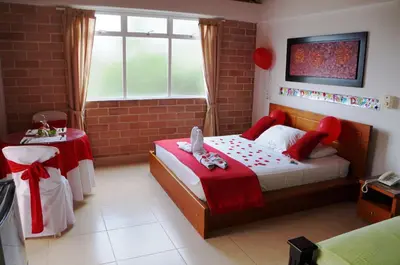 a bedroom with a bed and a table and a window at Hostería Fundadores in Santa Fe de Antioquia